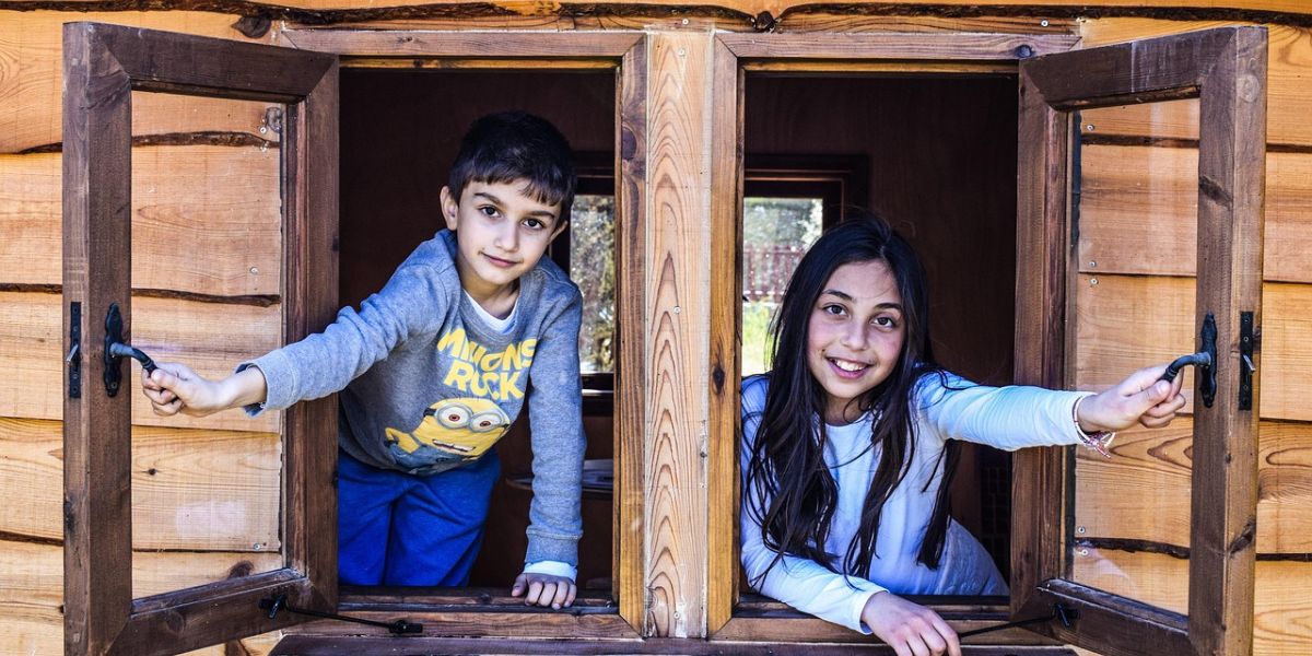 bambina e bambino affacciati alla finestra