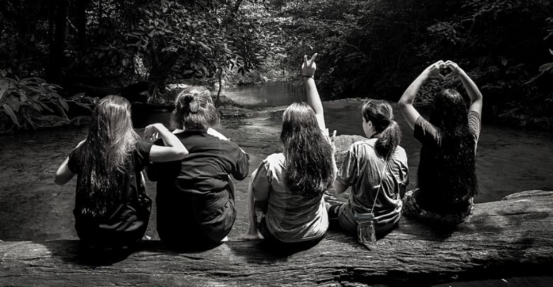 ragazze di spalle che guardano un fiume e vegetazione