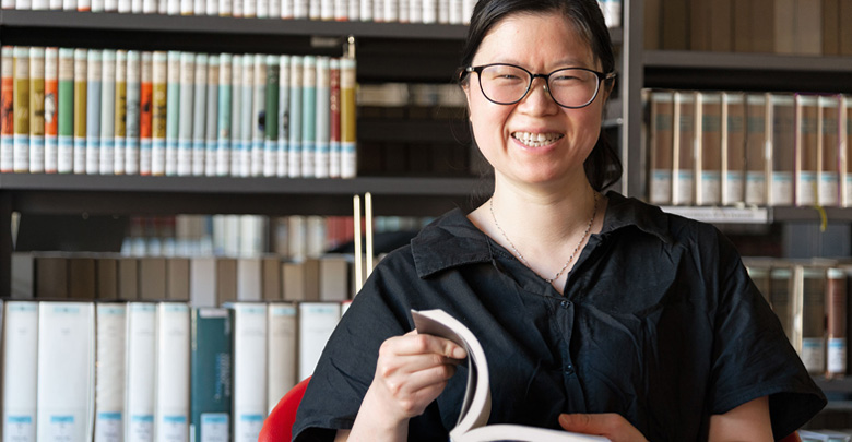 Studentessa cinese con libro in mano in Biblioteca