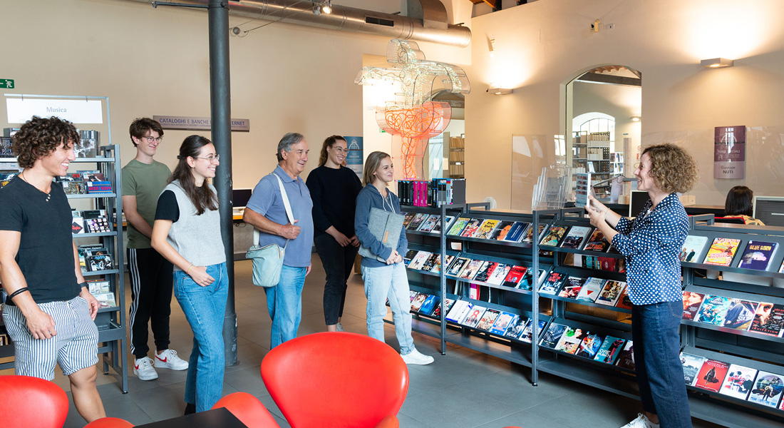 Un gruppo di persone ascolta la guida che illustra loro i locali della biblioteca