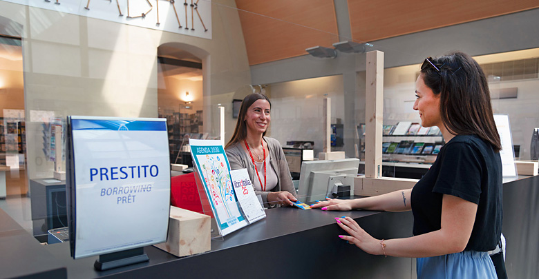 Bibliotecaria che consegna la tessera del prestito ad una utente