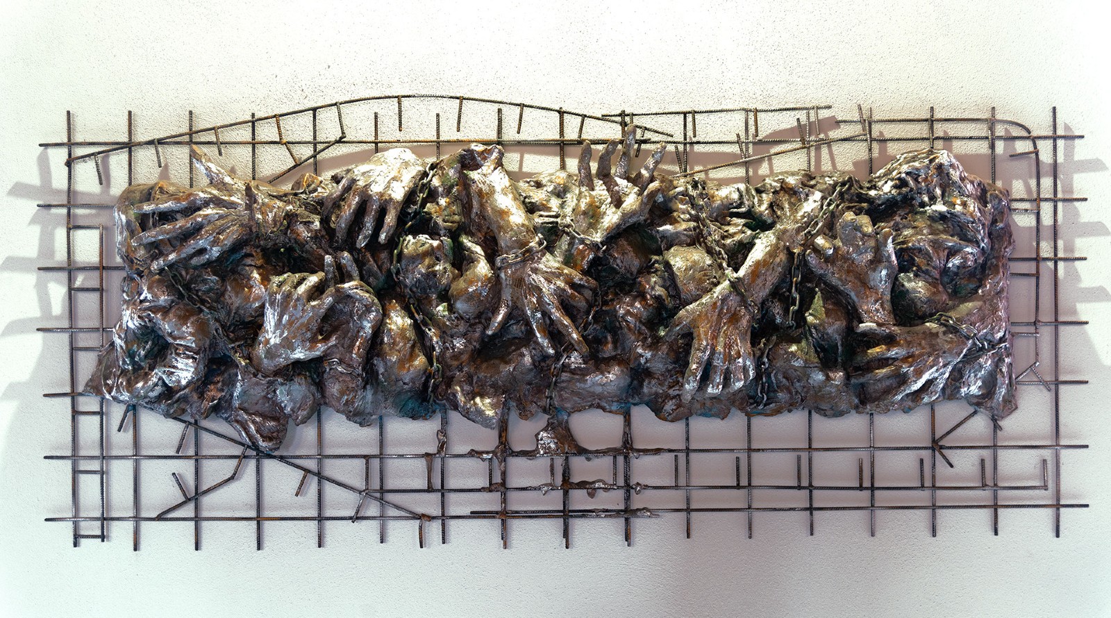 scultura in gesso che rappresenta un groviglio di mani legate con catene